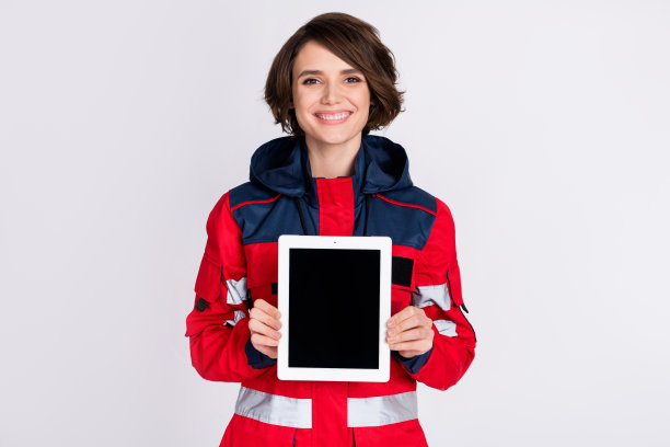 年轻美丽、微笑愉快的女救护员在灰色背景下展示平板电脑的照片图片下载