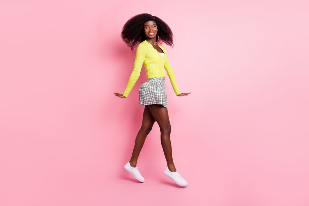 年轻美丽可爱的非洲女孩在粉色背景下走路的全身侧面照片图片下载