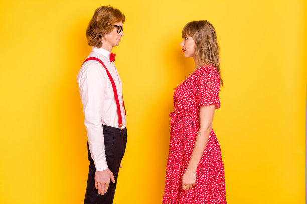 严肃的情侣在约会时互相凝视的照片肖像，背景为鲜艳的黄色。图片下载