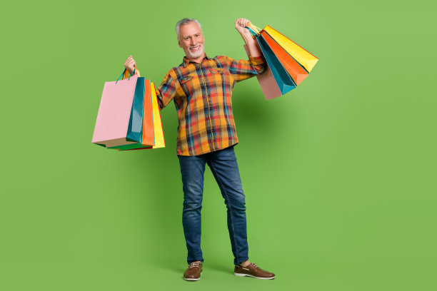 穿着衬衫、牛仔裤和鞋子的令人印象深刻的老年男子在绿色背景下购物的全身照片图片下载