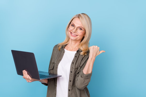 中年女性推广员在蓝色背景下展示空白空间的电子商店笔记本电脑照片图片下载