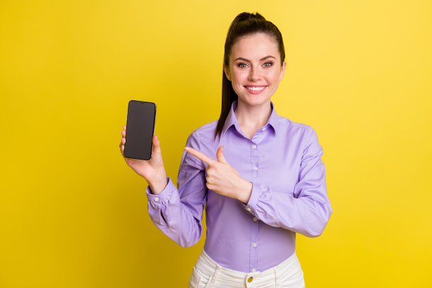 女性指着手机的照片肖像，手机屏幕上有空白空间，背景为明亮的黄色。图片下载