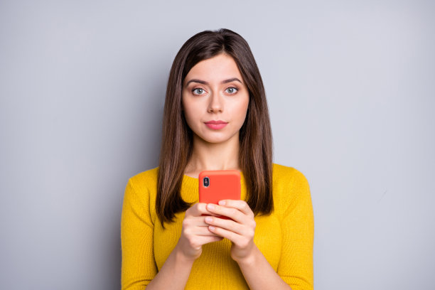 年轻、冷静、平和、迷人、可爱的女孩网红在灰色背景下使用智能手机的照片图片下载