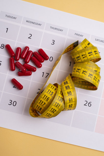 测量带和药片，维生素在浅色背景上，留有文本空间。减肥、节食、燃烧脂肪、健康饮食的概念。图片下载
