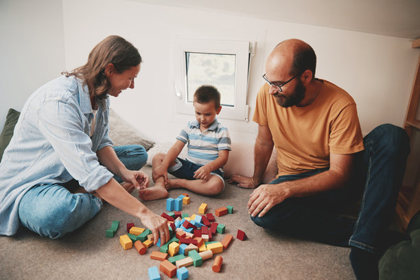 父母和他们的儿子在小卧室里玩耍的真实生活照片。微型房屋概念。图片下载