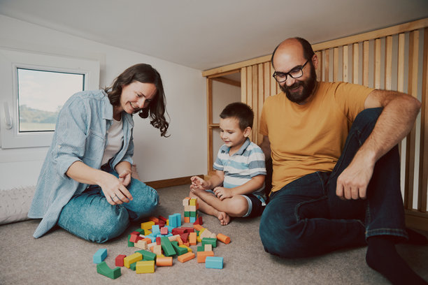 父母和他们的儿子在小卧室里玩耍的真实生活照片。微型房屋概念。图片下载