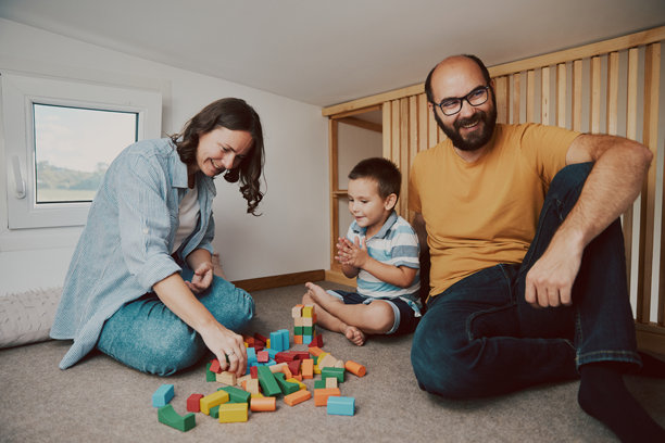 父母和他们的儿子在小卧室里玩耍的真实生活照片。微型房屋概念。图片下载