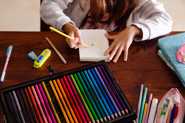 一个小女孩在给手绘图画上色。图片下载