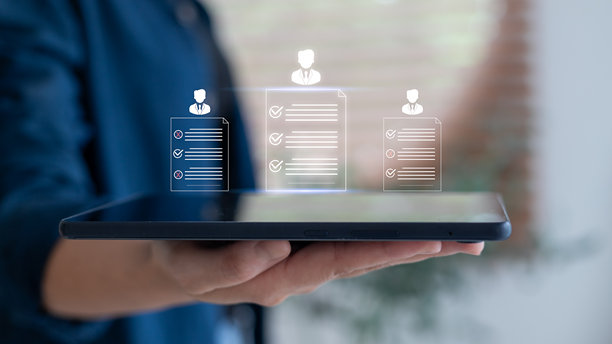 手握平板电脑的特写，显示数字简历清单和候选人资料图标，代表智能招聘、数字评估和现代人力资源技术。图片下载