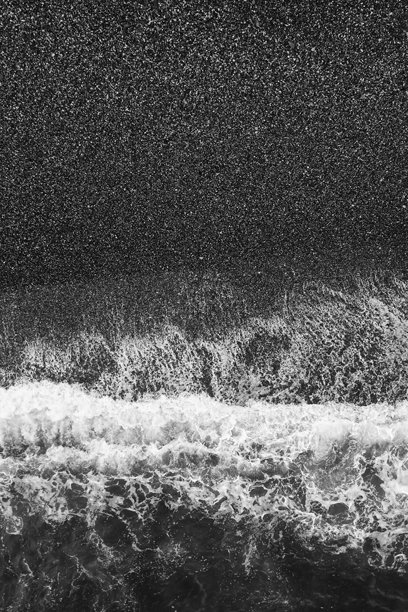 一张黑白照片，展示了波涛汹涌的海洋和一朵浪花。水面波动，天空阴暗。图片下载