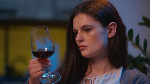 白人伤心的女人在家中夜晚喝着一杯酒，翻看相册，回忆着剪贴簿中的照片，独自思考，感到沮丧，沉迷于酒精，经历着抑郁和悲伤的危机。图片下载