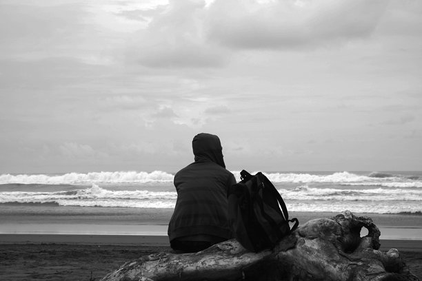 一名男子坐在帕朗特里蒂斯海滩的边缘，旁边是一幅黑白照片。图片下载