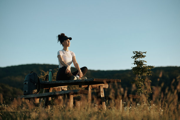 年轻美丽的女登山者的照片。她坐在木凳上，伸展身体，为徒步旅行做准备。图片下载