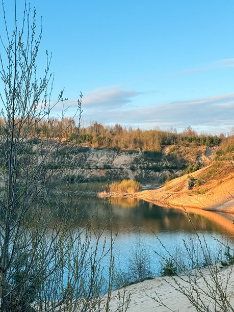 一个被遗弃的石材采石场，里面充满了美丽的蓝色水域，周围是沙质山脉和树木。竖版照片图片下载