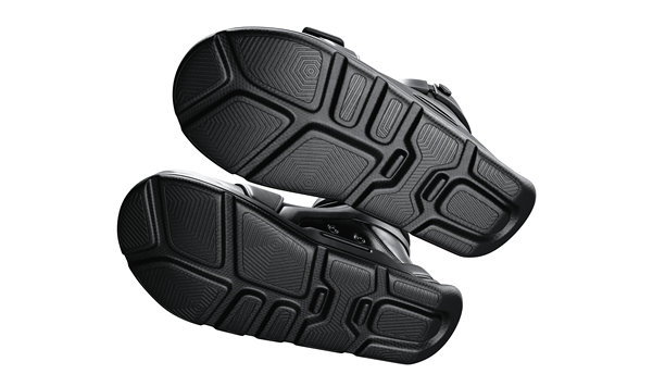 3D渲染的底部视图，展示了赛博朋克风格的黑色皮革运动鞋，配有自动系带机制、大型魔术贴带、红色LED后跟灯、厚橡胶鞋底和宽大的鞋头，背景为白色。图片下载