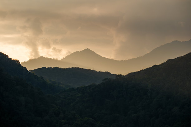 自然风光的照片，金色日落下的多云天空，山丘上有阴影和雾气。图片下载