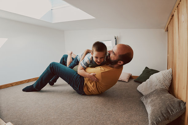 父亲和儿子的照片。他们在小房子的卧室里玩摔跤。图片下载