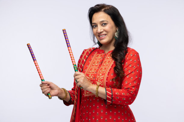 美丽的印度女性穿着传统的裙子和上衣在白色背景下表演丹迪亚舞的照片图片下载