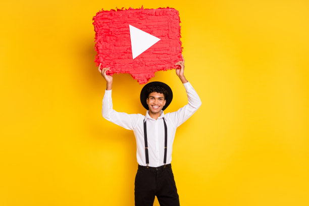 非洲裔美国男性手持红色播放按钮YouTube皮纳塔的照片肖像，背景为鲜艳的黄色。图片下载