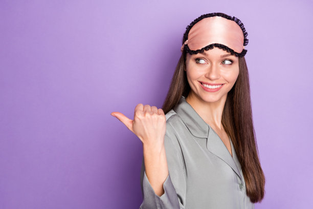 侧面肖像照片，快乐的年轻女性指着空白处，展示促销信息，背景为紫色。图片下载