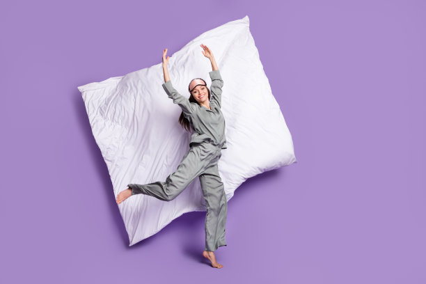 穿着睡衣的女孩在淡紫色背景下跳舞芭蕾，跳跃的全身照片，旁边有一条毯子。图片下载