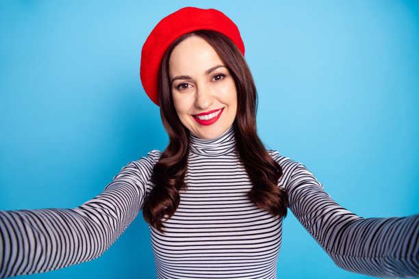 女人在鲜艳的蓝色背景前微笑着自拍，神情愉悦的照片肖像图片下载