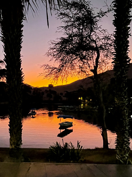 壮观的华卡奇纳泻湖垂直照片，夕阳下小船为游客提供美丽的景色图片下载