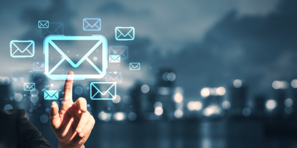 商人在夜晚模糊的城市背景下，点击发光的电子邮件图标，展现未来数字屏幕。图片下载