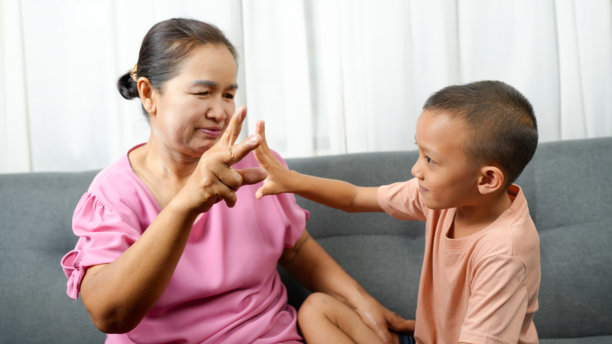 祖母与孙子之间快乐的互动被这张图片捕捉到。祖母穿着粉色上衣，和穿着浅色衬衫的男孩嬉戏玩耍。他们的表情反映出图片下载