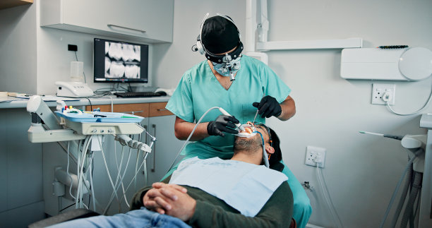 牙科诊所中接受口腔治疗的医生、男性或患者，进行牙贴面或医疗手术。预约、手术或口腔检查的患者，进行牙齿美白或美容治疗。图片下载