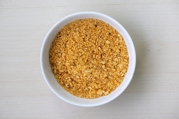 白色碗里装满美味的面包屑，放在木质表面上。非常适合用作油炸食品的酥脆涂层、肉丸的粘合剂，以及美味的砂锅菜顶料。高质量的食品库存图片。图片下载