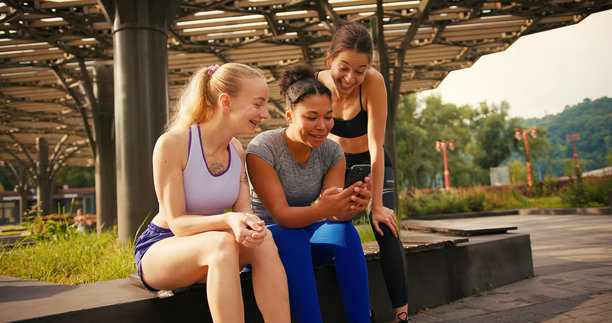 运动员坐在公园的长椅上浏览共享照片图片下载