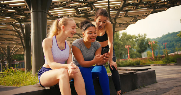 运动员坐在公园的长椅上浏览共享照片图片下载