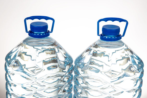 两个带蓝色盖子和独特波浪设计的塑料水瓶，孤立在白色背景上。适合健康、补水或环保产品的库存图片。图片下载