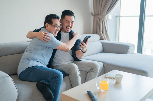 亚洲老年父亲与儿子在使用智能手机查看结果时收到好消息的照片图片下载