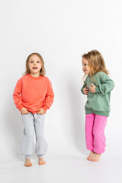 两个可爱搞笑的女孩在玩耍，享受乐趣。孩子们面带微笑，表情搞笑，背景明亮。竖版照片图片下载