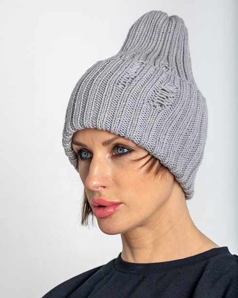 穿着灰色帽子的美丽女性肖像。穿着温暖衣物的漂亮女孩在灰色背景前。工作室摄影。竖版照片。图片下载