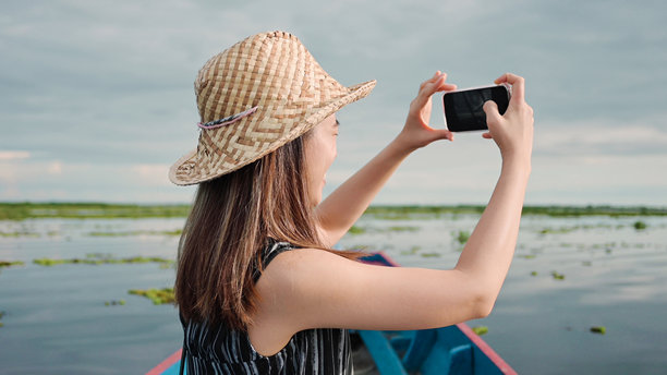 亚洲影响者Z世代女性用智能手机拍摄海滩照片，背景是海浪和天空图片下载