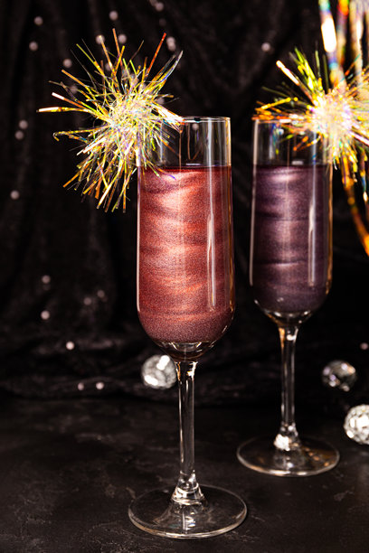 两杯带有可食用闪粉的新年鸡尾酒，黑色背景，竖版照片图片下载