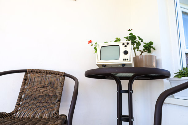 一台复古电视和一个花盆放在圆桌上的简约组合。这个画面营造出一种温馨、宁静的家庭氛围，象征着复古风格与现代室内设计的结合。图片下载
