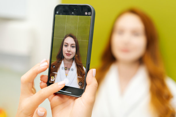 美容师使用智能手机拍摄女性在美容程序前的特写照片，以便记录和比较当前外貌。图片下载
