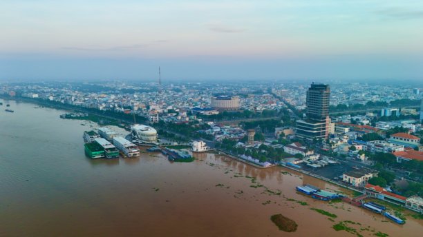 越南湄公河三角洲美拖市：日出航拍照片，水边、湄公河上的船只、码头、游轮港口、天际线、城市风光和现代河滨建筑图片下载