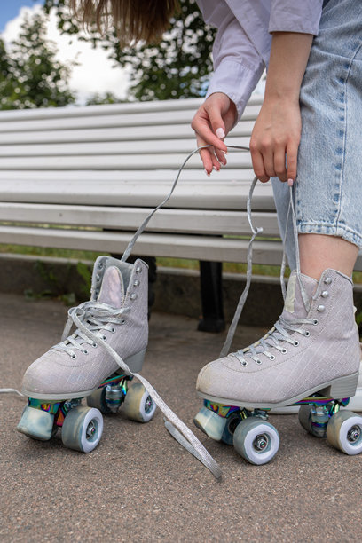 年轻情侣在公园里滑旱冰和滑板。快乐的女孩和男孩在温暖的夏日一起运动。竖版照片图片下载