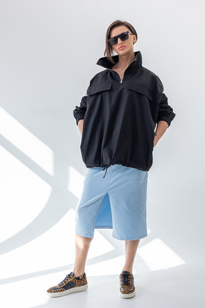 穿着黑色风衣和浅蓝色裙子的优雅女性，背景为白色。时尚女性风格。摄影棚拍摄。竖版照片。图片下载