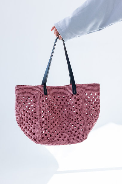 女性手持时尚粉色编织包。时尚与奢华配饰。竖版照片。图片下载