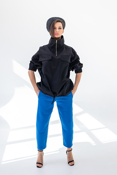 穿着黑色风衣夹克、蓝色裤子和海军帽的优雅女性，背景为白色。时尚女性展现海洋法式风格。摄影棚拍摄。竖版照片。图片下载