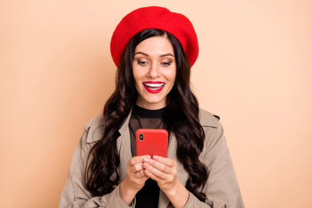 女性双手持手机的肖像照片，背景为柔和的米色。图片下载