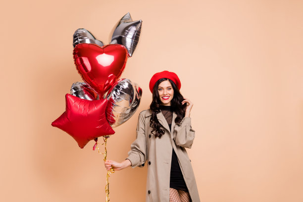 女性手持氦气球的照片肖像，背景为柔和的米色。图片下载