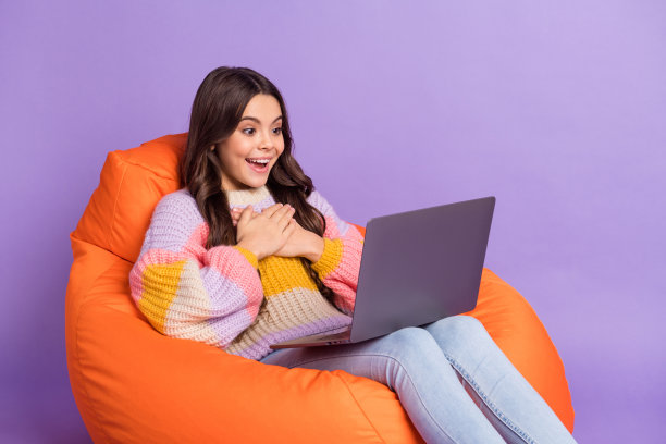 年轻女孩侧面头像，开心微笑，惊讶地看着笔记本电脑，背景为紫色。图片下载