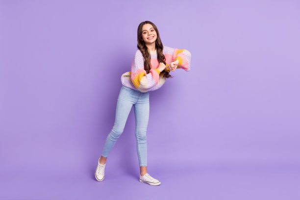 年轻快乐女孩的全身照片，开心地微笑，享受舞蹈，背景为紫色。图片下载